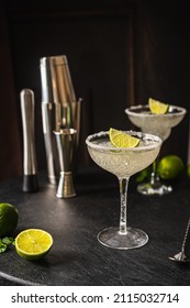 Margarita cocktail with lime and ice on dark wooden table with copy space. Classic Margarita and Daiquiri Cocktail.
