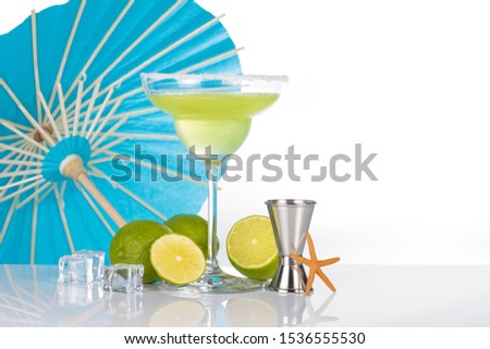 margarita cocktail, lime and jigger, umbrella on the background, isolated on white