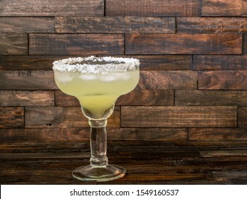 Margarita cocktail in a salt rimmed glass on a rustic wooden background with copy space. 