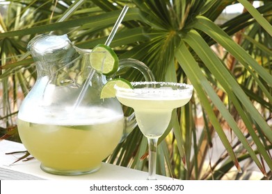 Margarita With Salt And Lime With Pitcher And Palm Tree In Background.