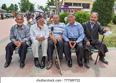 MARGILAN, UZBEKISTAN - MAY 16, 2017:  Elderly Uzbek local men sit on the bench in a park, in Margilan, Uzbekistan.