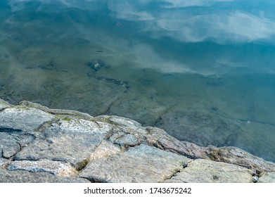 Margin Of Stones And Blue Water At Glades Bay Park In Lower North Shore