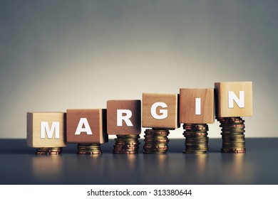 margin text written on wooden block with stacked coins on grey background - Shutterstock ID 313380644