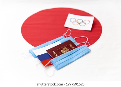 Mari El, Russia - June 16, 2021: The Russian Passport, Flag And Blue Masks. Olympic Flag On Red Round. The Japanese Flag Background. Tourist Trip. The Olympic Games