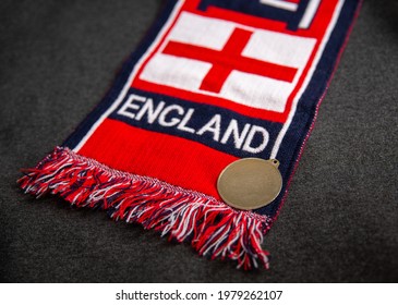 Mari El, Russia - May 10, 2021: Red Scarf Of A Great Britain Football Fan With The Inscription England. Golden Or Bronze Empty Medal