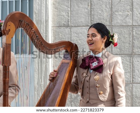 mariachi woman harpist smiling and having fun while playing harp