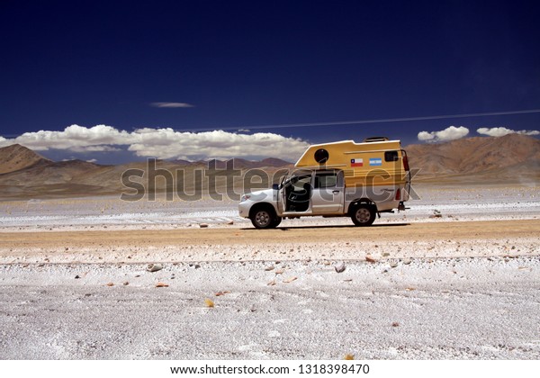 MARICUNGA SALT FLAT PLATEAU, CHILE - DECEMBER\
20. 2011. Isolated 4 wheel camper on white salt dirt road in arid\
dry lonely landscape