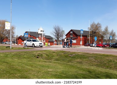 MARIEHAMN, ALAND ON MAY 07. View From A Small Town By The Sea On May 07, 2016 In Mariehamn, Aland. Unidentified People Cross The Road. Beacon And Red Buildings.