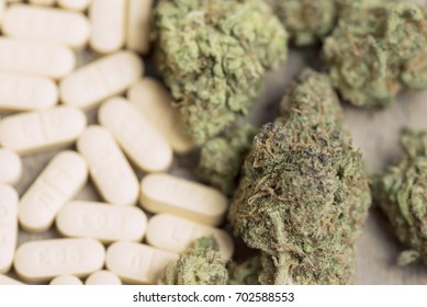 Marijuana Buds And Prescription Pills On Table. Macro Close Up, With 50/50 Split Between Cannabis And Pills. 