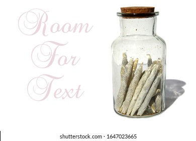 Marijuana. Cannabis Cigarettes AKA Joints in a Glass Stash Jar. Isolated on white. Room for text. Marijuana is legal in many of the United States for Recreation and Medical use. Enjoy some today. 