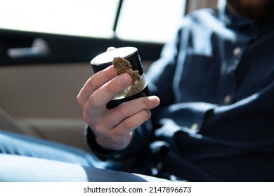 Marijuana Joint In Hand Bud Flowers Of Cannabis. Grinder And Shredded Cannabis Joint Packet Of Weed On A Car Background Close Up