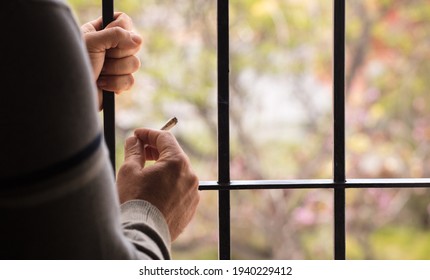 Marijuana Joint Lit, In The Hands, With Prison Gate And Forest In The Background