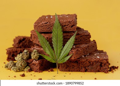 Marijuana leaf in front of nicely displayed stacks of delicious chocolate fudge brownies
