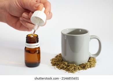 marijuana oil dropper bottle in man's hands with infusion cup, crushed marijuana, white background