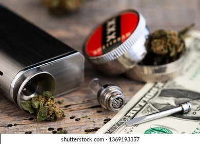 Marijuana Vaporizer With Grinder And US Dollar Bill On Wooden Background.