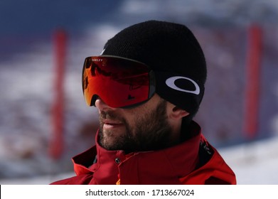"Marilleva, Trento - Genuary 15 2019" Beautiful man skier pose with OAKLEY ski and snowboard mask Flight Deck Prism, SALOMON red jacket, on snow mountain background in ski slope in a winter sunny day