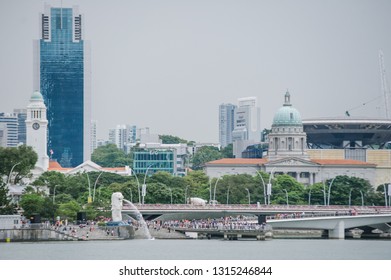 Marina Bay, Singapore - February 15, 2019 - Breathtaking View Of The Marina Bay And Merlion Statue Standing Far At Marina Bay Sands. Close Up On The Group Of The Building Details And The Logo.