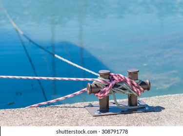 Marina bollard (bitt) at jetty for boats, ships and yachts mooring. Ã�Â¡lose up of rope tied up on a bitt. blue water in the background