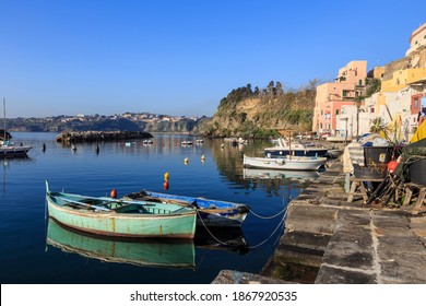 Marina Corricella, Procida Island, Campania, Italy - 03 16 17: Focus on small boats reflected in the calm blue water of a quiet port on a Bay of Naples island