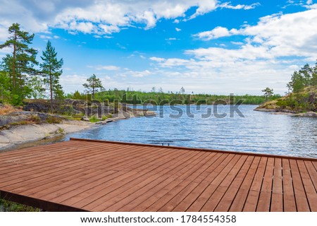 Marina at the forest lake. Boat dock on the background of the lake. Wooden flooring against the background of water and rocky banks.
