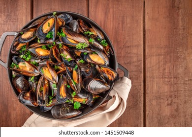 Marinara Mussels, Moules Mariniere, In A Cooking Pot, Overhead View, Shot From The Top On A Dark Rustic Wooden Background With A Place For Text