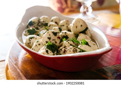 Marinated bocconcini baby mozzarella salad with basil served in oval porcelain lasagna baking dish