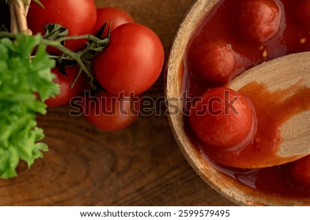 Marinated cherry tomatoes, tomato paste in its own juice in a wooden spoon and in a wooden plate on a wooden board background. Canned food, natural tomato paste. Cooking.