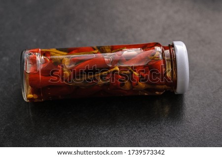 marinated chili pepper in a jar on a dark background on the table