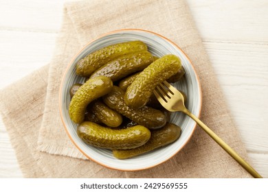 Marinated gherkins in a bowl on a light wooden background. Homemade pickles. Close-up - Powered by Shutterstock