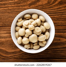 Marinated mushrooms in a plate close-up on a wooden background. Top view - Powered by Shutterstock