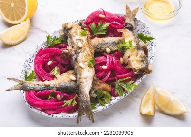 Marinated  sardines or Sarde in saor, a typical dish from the Venice, Italy  with white onions marinated with wine vinegar, raisins and pine nuts, served with bread