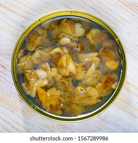Marinated shellfish in an open tin can on wooden table