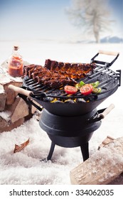 Marinated spare ribs and colorful vegetables cooking on a winter barbecue outdoors in a snowy landscape