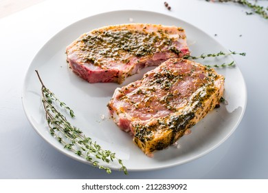 Marinated uncooked pork chops on white plate. Marinated pork steak ready for cooking, Meat for BBQ, Garlic and herbs marinate. Organic raw pork steak