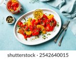 Marinated yellow and red bell pepper salad with capers and olive oil. Blue background. Top view.