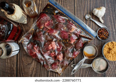 Marinating Raw Steak Tips in a Plastic Ziplock Bag: Uncooked beef tips in a plastic bag surrounded by marinade ingredients
