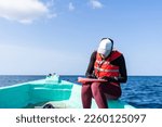 Marine biologist writing down data sitting on top of a boat in the middle of the sea