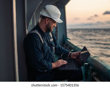 Marine chief officer or captain on deck of vessel or ship watching laptop. Internet and home connection at sea.