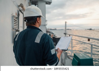 Marine Deck Officer or Chief mate on deck of offshore vessel or ship doing check and filling checklist. Paperwork at sea. Ship is on background