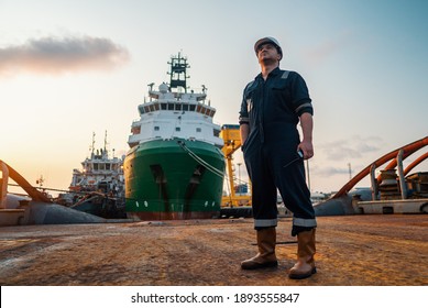 Marine Deck Officer or Chief mate on deck of offshore vessel or ship , wearing PPE personal protective equipment - helmet, coverall. Ship is on background - Shutterstock ID 1893555847