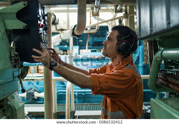 Marine engineer inspecting ship\'s engine\
in engine control room ECR. Seamen\'s\
work.
