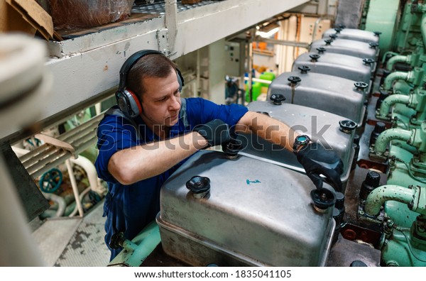 Marine\
engineer officer reparing vessel engines and propulsion in engine\
control room ECR. Ship onboard\
maintenance