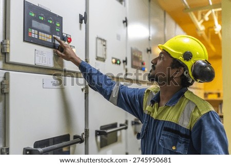 Marine engineer operating the generator control panel inside the engine room, monitoring onboard power production on a commercial vessel.