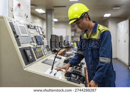 Marine engineer operating main engine control panel inside the ship’s engine control room, managing propulsion systems of a commercial cargo vessel.