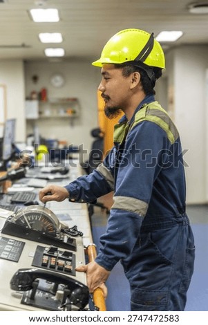 Marine engineer operating main engine control panel inside the ship’s engine control room, managing propulsion systems of a commercial cargo vessel.