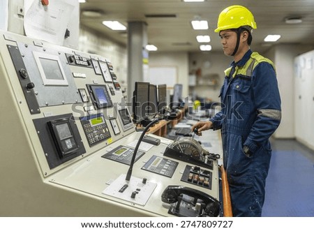 Marine engineer operating main engine control panel inside the ship’s engine control room, managing propulsion systems of a commercial cargo vessel.