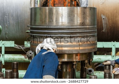 Marine engineer works on assembling of piston in the large double stroke main engine of merchant ship.