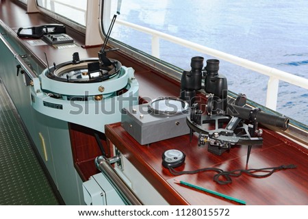 Marine navigation instruments on the bridge of ship at sea: sextant, chronometer, navigation map and binoculars