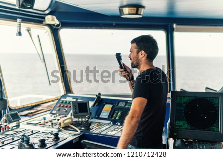 Marine navigational officer is reporting by VHF radio during navigation watch. Bridge GMDSS watch