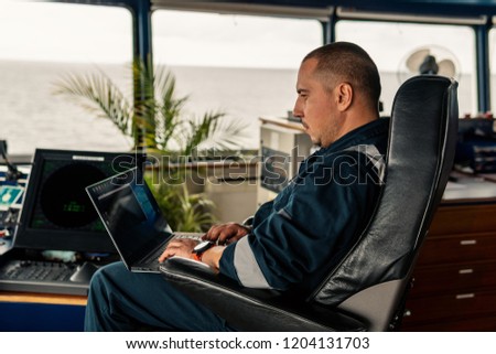 Marine navigational officer or technician is using laptop or notebook at sea. Job at sea
